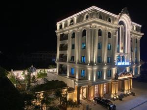 een groot wit gebouw met 's nachts blauwe lichten bij Minh Đức Hotel 