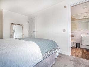 a white bedroom with a bed and a bathroom at Springfield in Dornoch