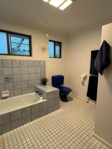 ein Badezimmer mit einer Badewanne und einem blauen WC in der Unterkunft Amongst the Trees in Mooloolah