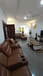 a living room with brown leather furniture and a piano at Anc mall area east legon guest house in Accra