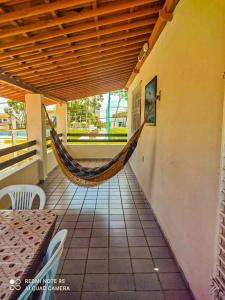 a hammock in a porch with a table and chairs at Casa em Ponta Negra in Natal
