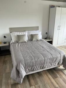 a white bedroom with a large bed with pillows at Monoambiente vista lateral en Pinamar in Pinamar