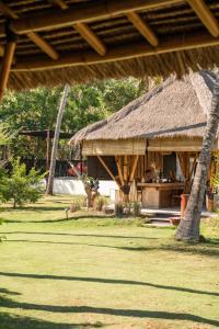 a hut with a grass roof on a field at Ama-Lurra Resort in Gili Air