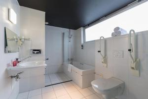 a white bathroom with a sink and a toilet at Leonardo Hotel Almere City Center in Almere