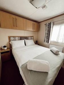 a bedroom with a large white bed and a window at Melrose in Leysdown-on-Sea