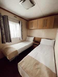 a room with two beds and a window at Melrose in Leysdown-on-Sea