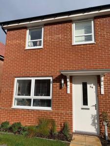 uma casa de tijolos vermelhos com uma porta branca em New Comfy Family Friendly home in Canterbury em Sturry