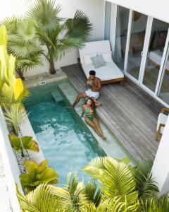 a man and a woman in a swimming pool on a balcony at Neptune Studios Lombok in Kuta Lombok