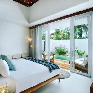 a bedroom with a large bed and a balcony at Neptune Studios Lombok in Kuta Lombok