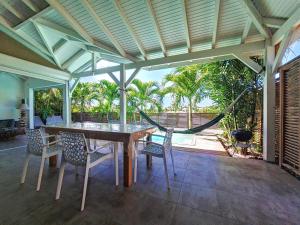a patio with a table and chairs and a hammock at cannelle in Sainte-Anne