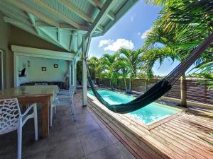 a porch with a hammock and a swimming pool at cannelle in Sainte-Anne