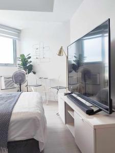 um quarto branco com uma televisão de ecrã grande numa secretária em Cozy Condo with City View em San Fernando