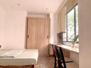 a bedroom with a bed and a desk and a window at PJ Hotel & Apartment - Thao Dien in Ho Chi Minh City