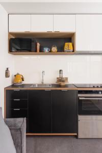 a kitchen with black and white cabinets and a sink at MAC Middle Park by Melbourne Apartment Collection in Middle Park