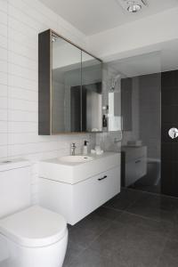 a bathroom with a toilet and a sink and a mirror at MAC Middle Park by Melbourne Apartment Collection in Middle Park