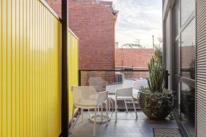 a balcony with chairs and a table and a building at MAC Middle Park by Melbourne Apartment Collection in Middle Park