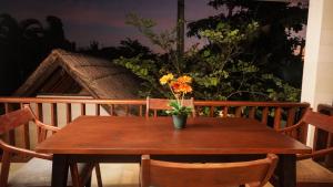 un tavolo di legno con un vaso con dei fiori sopra di Suite by the Sea Apartment Seminyak a Seminyak