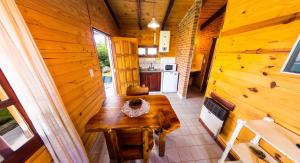 ein Holzzimmer mit einem Holztisch und einer Küche in der Unterkunft Altos Del Bosque in Villa Yacanto