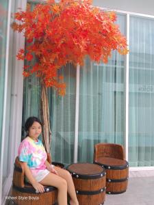 a young girl sitting on a chair next to a tree at Love Here Poolvilla หัวหิน in Hua Hin