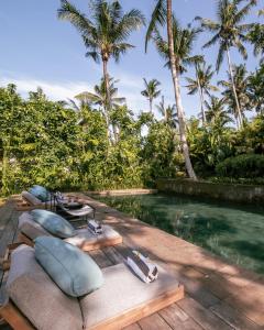 een resort met een zwembad en palmbomen bij Villa Bedulu Cliff Estate Ubud - Wood Side in Ubud