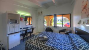 ein Schlafzimmer mit einem Bett und eine Küche mit einem Tisch in der Unterkunft Twin Swans Motel in Inverell