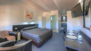 a hotel room with a bed and a table and chairs at Twin Swans Motel in Inverell