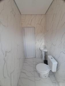 een witte badkamer met een toilet en een wastafel bij Casa do Enzo in Peruíbe