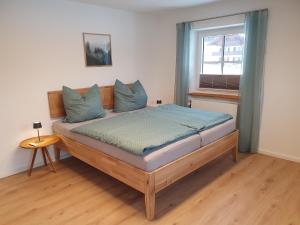 a bedroom with a bed with blue pillows and a window at Ferienwohnungen Winkler in Bischofswiesen