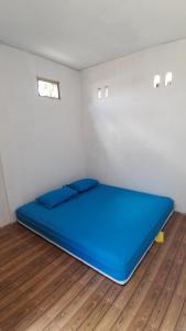 Cama grande azul en habitación con suelo de madera en Sollo Sollo Homestay en Lemonga