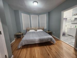 a bedroom with a bed with blue walls and wooden floors at Mins to NYC, Cosy 3 Bedroom Apartment in Jersey City