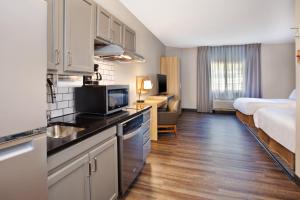 a room with a kitchen and a bedroom with a bed at Candlewood Suites Kenosha, an IHG Hotel in Pleasant Prairie