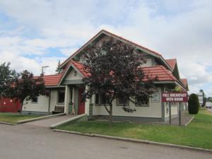 a house with a tree in front of it at Stork Nest Inn in Smithers