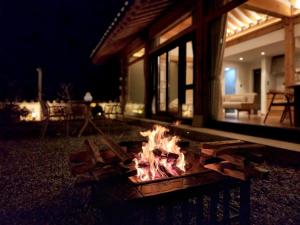 una hoguera frente a una casa por la noche en Hotelarrive Taean Tiann HanokBeachResort, en Taean