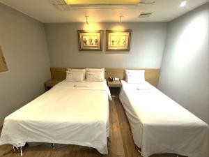 Urban Nest Hotel في سول: سريرين في غرفة ذات أغطية بيضاء