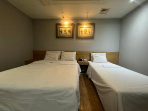 two beds in a room with white sheets at Urban Nest Hotel in Seoul