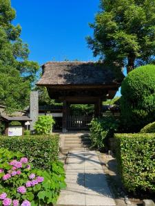 a pavilion with a roof in a garden with flowers at 極楽寺邸 - Gokurakuji House in Kamakura