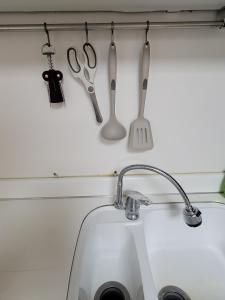 a kitchen counter with utensils hanging above a sink at White Stay in Seoul