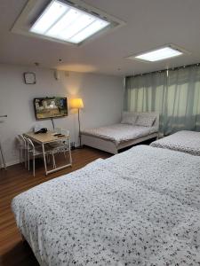 a bedroom with two beds and a table and a television at White Stay in Seoul