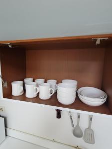 a shelf with white dishes and utensils on it at White Stay in Seoul