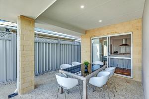 a balcony with white chairs and a table and a kitchen at MOSS1 - Bunbury Chic Villa Retreat by the Beach in Bunbury