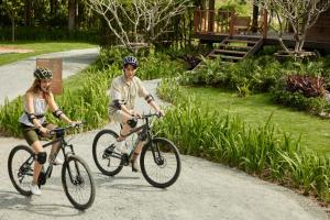a man and woman riding bikes down a path at Tantawan Tented Camp Chiang Rai in Mae Chan