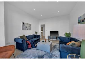 a living room with two blue couches and a tv at Astonishing 4BR House - Perfect for a Big Family in Southend-on-Sea
