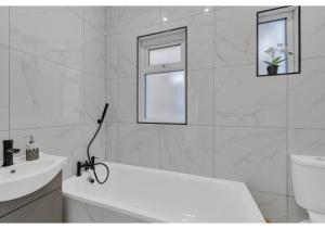 Baño blanco con bañera y lavamanos en Astonishing 4BR House - Perfect for a Big Family, en Southend-on-Sea