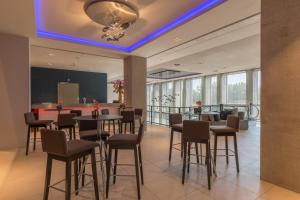 a restaurant with tables and chairs and a bar at Leonardo Royal Hotel Amsterdam in Amsterdam