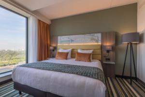 a bedroom with a large bed with a large window at Leonardo Royal Hotel Amsterdam in Amsterdam