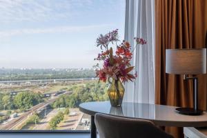 a vase of flowers on a table in front of a window at Leonardo Royal Hotel Amsterdam in Amsterdam