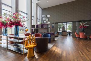 a lobby with chairs and flowers in a room at Leonardo Royal Hotel Amsterdam in Amsterdam