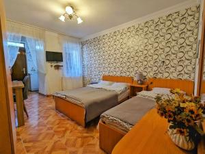 a bedroom with two beds and a table with flowers at Paata's Guesthouse in Borjomi