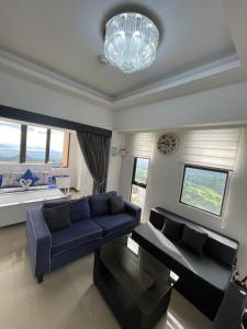 ein Wohnzimmer mit einem blauen Sofa und einem Kronleuchter in der Unterkunft Splendido Tower 2 Ann's Unit in Tagaytay