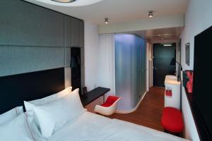 a hotel room with a bed and a red chair at citizenM Menlo Park in Menlo Park